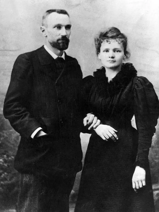 Photographie de Pierre et Marie Curie en 1895, debout côte à côte, elle lui tient le bras