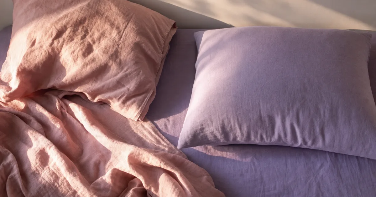 Un lit vu de dessus avec deux oreillers : l'un froissé, le drap rabattu, l'autre parfaitement lisse et intact